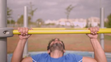 Male pull up workout steps. Caucasian man hanging on a bar to working out at city park. Calisthenics body building activity. Gym workout and sport excercise concept.