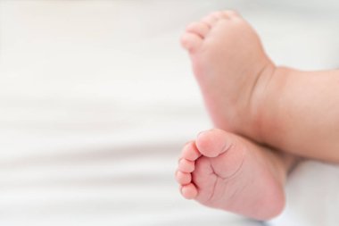 A foots of the newborn on a white sheet background. Tiny foot of a baby boy. Family and home concept with copy space.