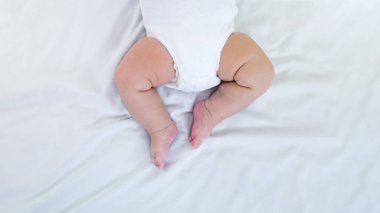 Küçük tombul bacaklı, beyaz çarşaflı, gün ışığında bir bebek. 3 aylık şirin bir bebek. Çocuk annesinin yatağında uyuyor. Aile anneliği kavramı