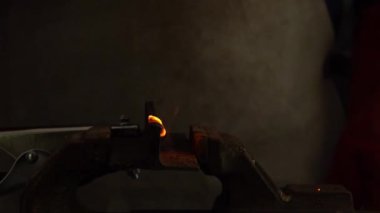 Atölyede kaynak makinesiyle çalışan bir zanaatkarın yavaş çalışması. Kıvılcımları farklı yönlere uçan bir demir parçası. Erkek işçi el kaynak makinesi..