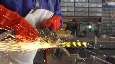 Slowmotion of metal processing with a man using angle grinder to cleaning the steel seam. Locksmith in special clothes and gloves works in production. Sparks in metalworking.