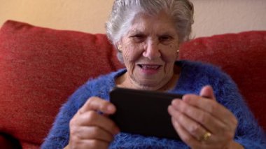 Mutlu gülümseyen yaşlı kadın konuşmak için akıllı telefonu kullanırken el ele düşmüş. Büyükanne telefon görüşmesi yaparken merhaba.