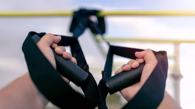 Kapalı eller sporcu TRX sistemi ile dışarıda çalışıyor. Şehir parkında vücut direnci egzersizleri. Yakışıklı bir adam sokak spor salonunda çalışıyor. Vücut geliştirici spor yapar.