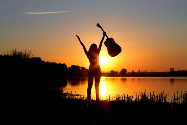 Silhouette of a happy girl with a guitar on the nature — Stock Photo, Image