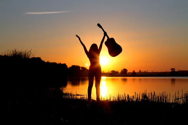 Silhouette d'une fille heureuse avec une guitare sur la nature — Photo