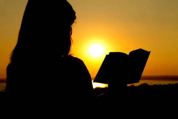 Silhouet van een meisje van lezend bij zonsondergang — Stockfoto