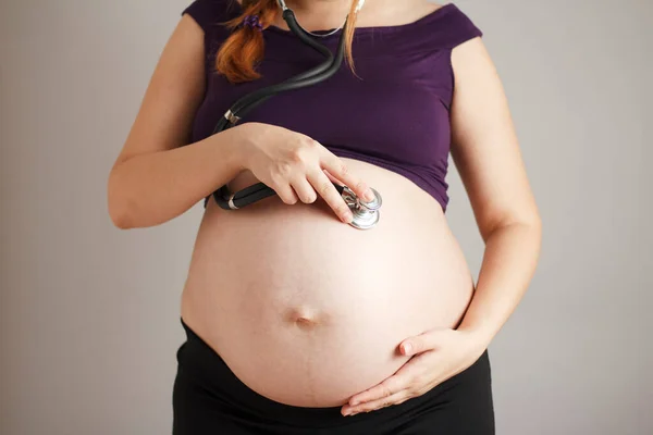 Gravid Kvinna Lyssnar Med Ett Stetoskop Magen Grå Studio Bakgrund — Stockfoto