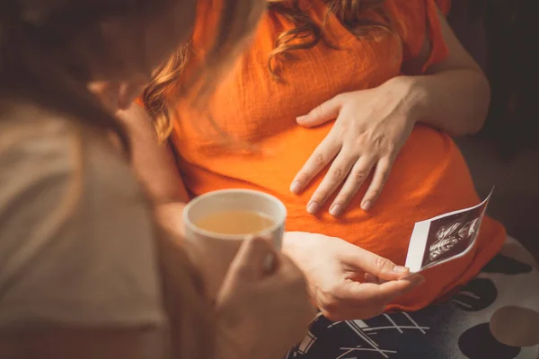 부엌에 임신부와 여동생 초음파 스냅샷 개념에 이야기하는 — 스톡 사진