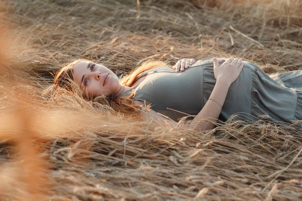 白种人怀孕的年轻红头发女子 夏天黄昏时分躺在麦田里 未来的母亲在大自然中放松 健康快乐的怀孕观念 新的生命 — 图库照片