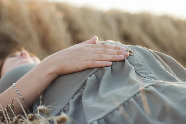 夏の麦畑に寝そべっている若い女性が腹に触れ未来の母親が自然をリラックスし健康的な妊娠家族の概念 — ストック写真