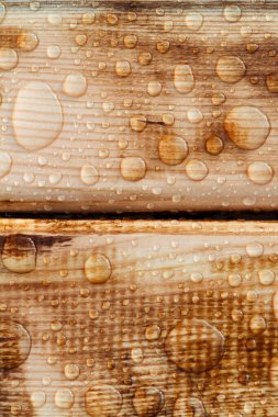 Yağmurdan parlak su damlaları, ıslak ahşap kalaslar, üst manzara.