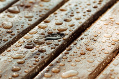 Islak ahşap döşeme tezgahları, ahşap dokunun arka planında yağmurdan düşen su damlaları.