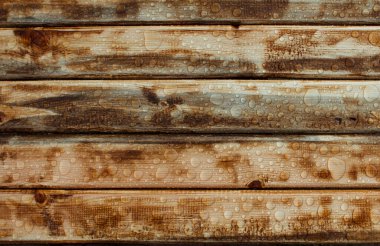 Yağmurdan parlak su damlaları, ıslak ahşap kalaslar, üst manzara.