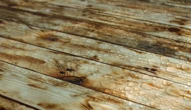 Yağmurdan yağan parlak su damlaları ve ıslak ahşap kalaslarla kaplanmış ahşap kaplama.