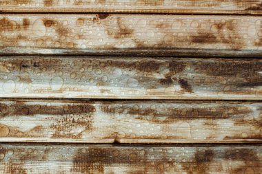 Yağmurdan parlak su damlaları, ıslak ahşap kalaslar, üst manzara.