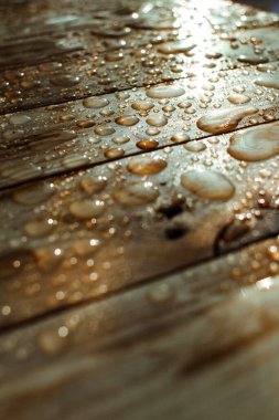 Yağmurdan yağan parlak su damlaları ve ıslak ahşap kalaslarla kaplanmış ahşap kaplama.