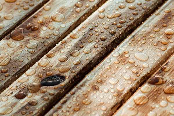Yağmurdan parlak su damlaları, ıslak ahşap kalaslar, üst manzara.