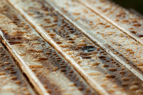 Yağmurdan yağan parlak su damlaları ve ıslak ahşap kalaslarla kaplanmış ahşap kaplama.