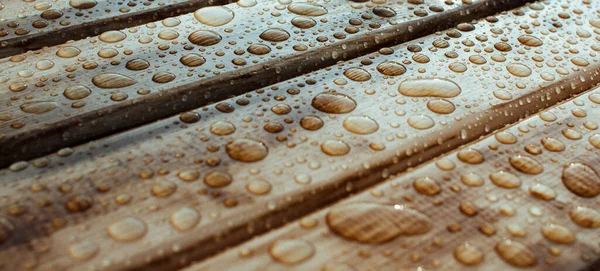 Yağmurdan yağan parlak su damlaları ve ıslak ahşap kalaslarla kaplanmış ahşap kaplama.