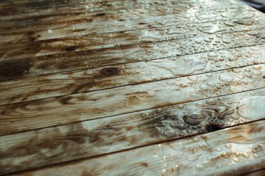 Yağışlı su damlaları ve yağmurdan oluşan su birikintileri, ıslak ahşap kalaslar.