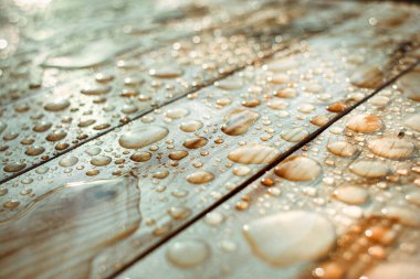 Yağışlı su damlaları ve yağmurdan oluşan su birikintileri, ıslak ahşap kalaslar.