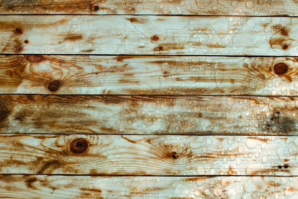 Yağmurdan parlak su damlaları, ıslak ahşap kalaslar, üst manzara.