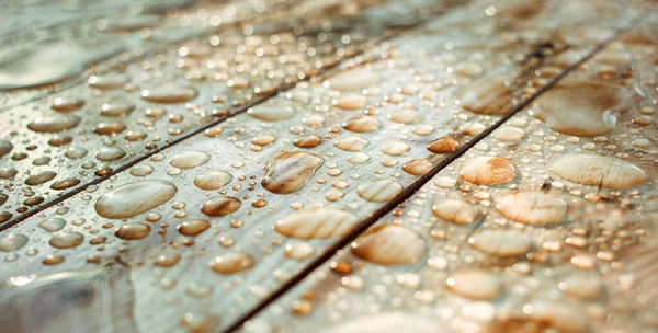 Yağışlı su damlaları ve yağmurdan oluşan su birikintileri, ıslak ahşap kalaslar.