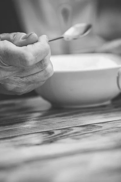 Elderly woman hand holding spoon over plate. Cocept of care for parents, life