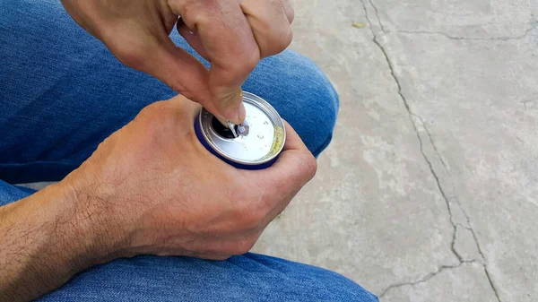 Bir adam alüminyum kutuyu içkiyle tutar, diğer eliyle açar. yakın plan.