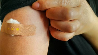 Aşı yapıldıktan sonra kimliği belirlenemeyen birinin kolundaki yapışkan bandaja yakın çekim yapılınca insanlar COVID-19 Coronavirus 'a karşı aşı oldular. Önerilen aşı önerisi.