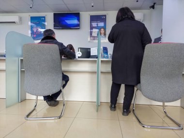 Erevan, Ermenistan - 22 Mart 2022. Bankadaki insanlar bir banka çalışanıyla mali işlemler yapıyorlar. Banka bekleme odası. Finansal hesaplamalar. Banka faaliyetleri.