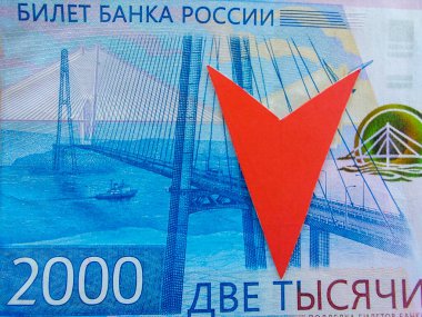 Rublonun düşük maliyeti kavramı. Rus bankasının iki bininci banknotunun bir parçası. Rublenin değerinin azaldığını gösteren kırmızı bir ok. Rus para biriminin düşüşü..
