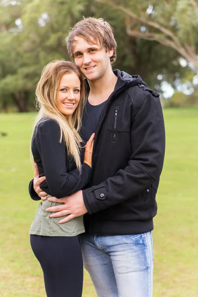 Jovem casal alegre abraçando e sorrindo em um parque — Fotografia de Stock