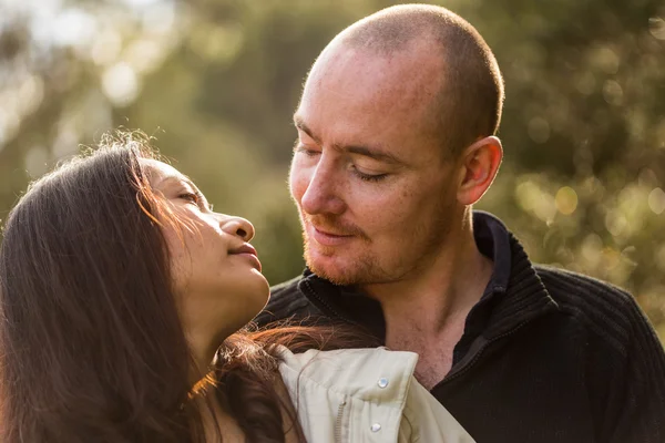 Romántico joven pareja retrato, mujer asiática, hombre caucásico, abrazos tiernamente en el ambiente al aire libre y hermosa luz — Foto de Stock