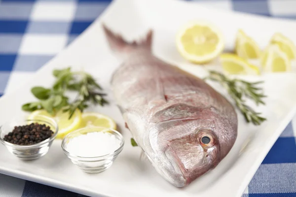 Un orata rossa con spezie, fette di limone ed erbe aromatiche — Foto Stock