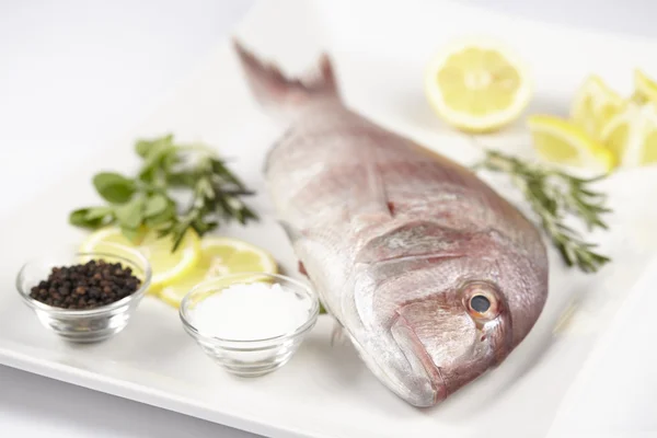 A red sea bream with spices, lemon slices and herbals — Stock Photo, Image