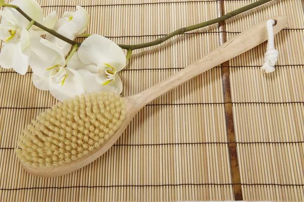 Brosse de bain sur un tapis de bambou et une orchidée — Photo