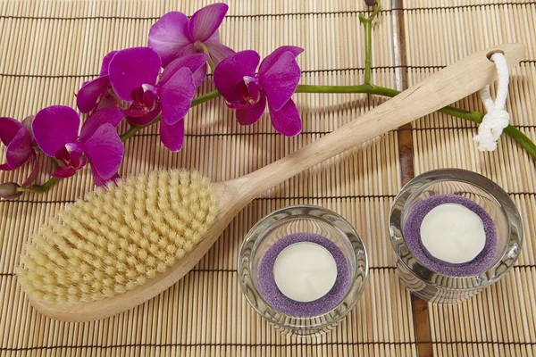 Cepillo de baño, orquídea y candelabros sobre una alfombra de bambú — Foto de Stock