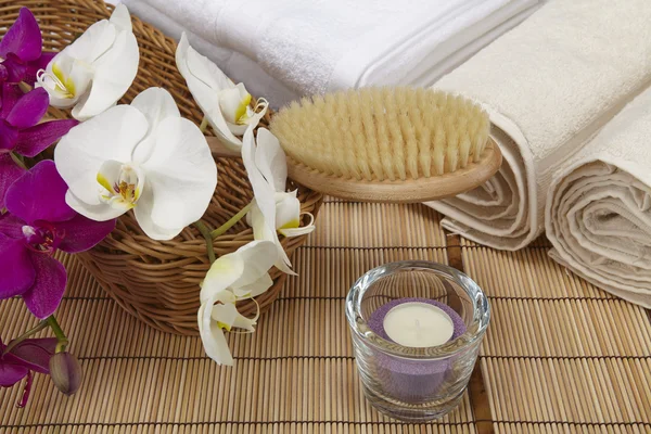 Bath brush, rolled towels, tealight and orchids — Stock Photo, Image