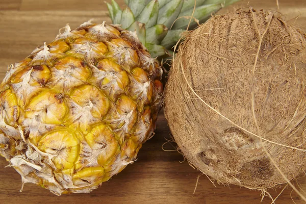 Pineapple and coconut on an acacia tabletop - close shot — Stock Photo, Image