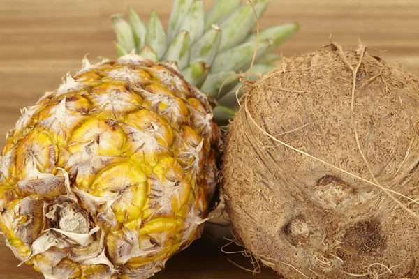 Pineapple and coconut on an acacia tabletop - close shot — Stock Photo, Image