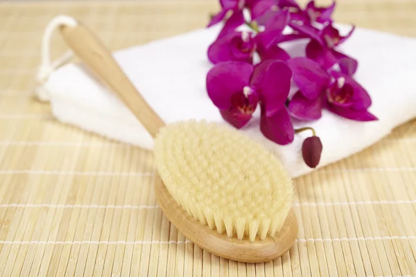 Sağlık - orkide ile katlanmış bir havlu üzerine banyo fırçası — Stok fotoğraf