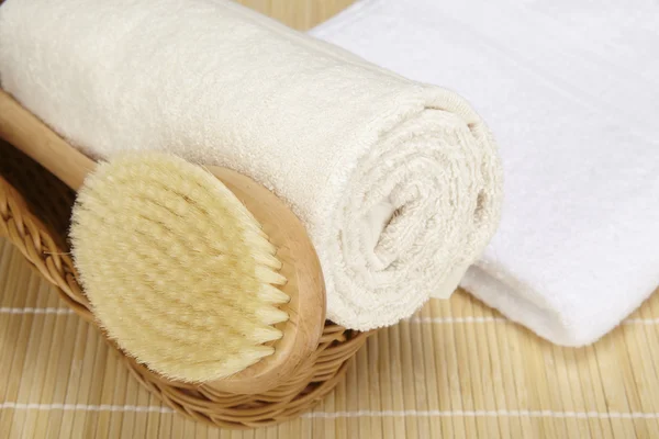 Bath brush and rolled towel in a basket — Stock Photo, Image