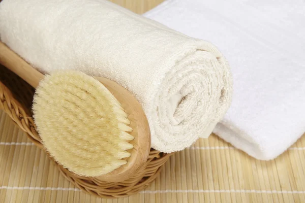 Bath brush and rolled towel in a basket Royalty Free Stock Photos