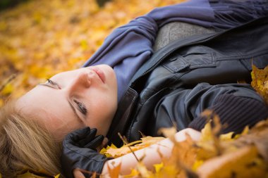 bir sonbahar yaprakları üzerinde yatan genç güzel kız