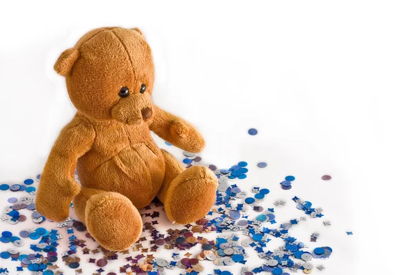 Teddy bear zit op blauwe confetti — Stockfoto