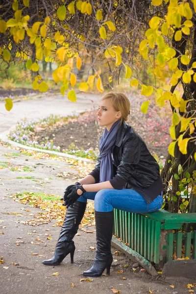 Traurige junge Frau sitzt neben Herbstbaum — Stockfoto