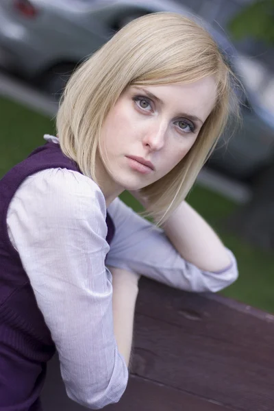 Sad young beautiful girl sit on a bench — Stock Photo, Image