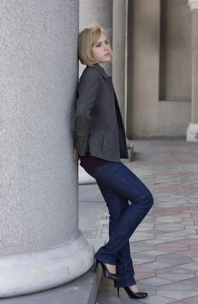 Sad beautiful young girl near columns — Stock Photo, Image