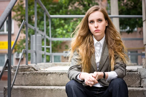 Sad woman sits on the staircase — Stock Photo, Image